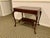 A vintage two-tier mahogany accent side table in a warm reddish-brown finish with visible grain figuring with a...