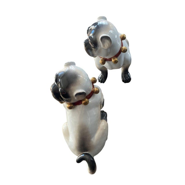 A charming pair of large English porcelain pug dog figures dating to the early 20th century. Each figure is expressively...