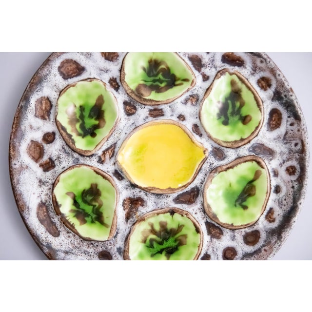 A vibrant Mid-Century French green and yellow majolica oyster plate in the Vallauris style, six wells with a lemon center.
