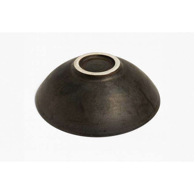 A wide bowl with a gently sloping rim, finished in rich tones of charred black and brown. The surface carries gorgeous...