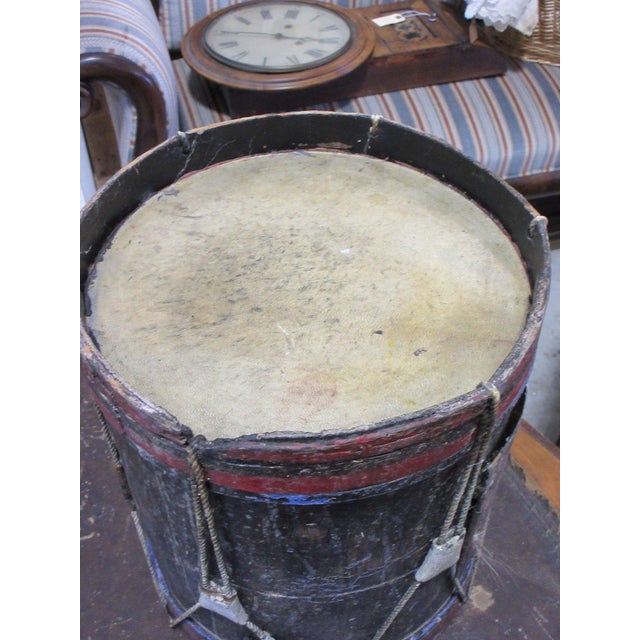 Antique wooden drum, believed to date to the Civil War era, with a dark painted body and worn red and blue painted bands...