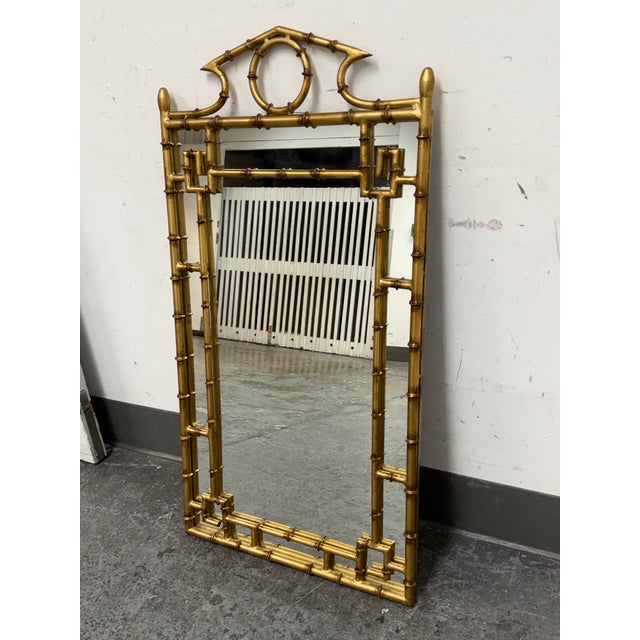 Design Plus Gallery presents a Regency Style Giltwood Faux Bamboo Wall Mirror. The rectangular mirror is framed in faux...