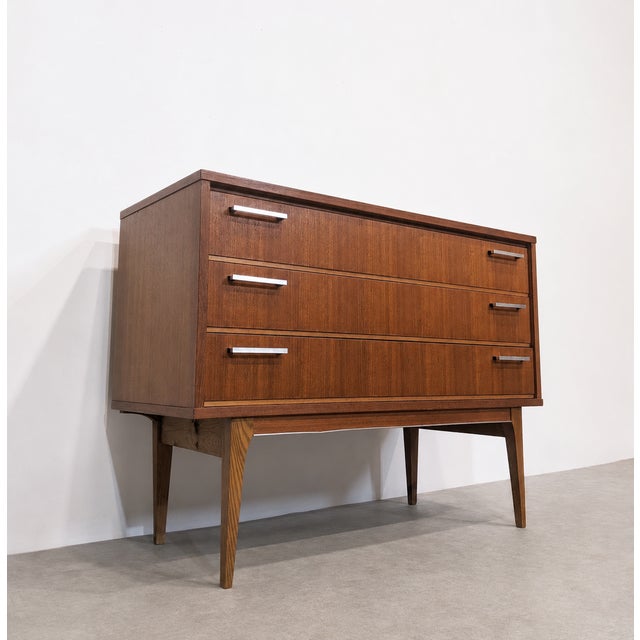 Mid-Century Modern style chest of drawers in teak veneer. The piece features three large drawers, minimalist rectangular...