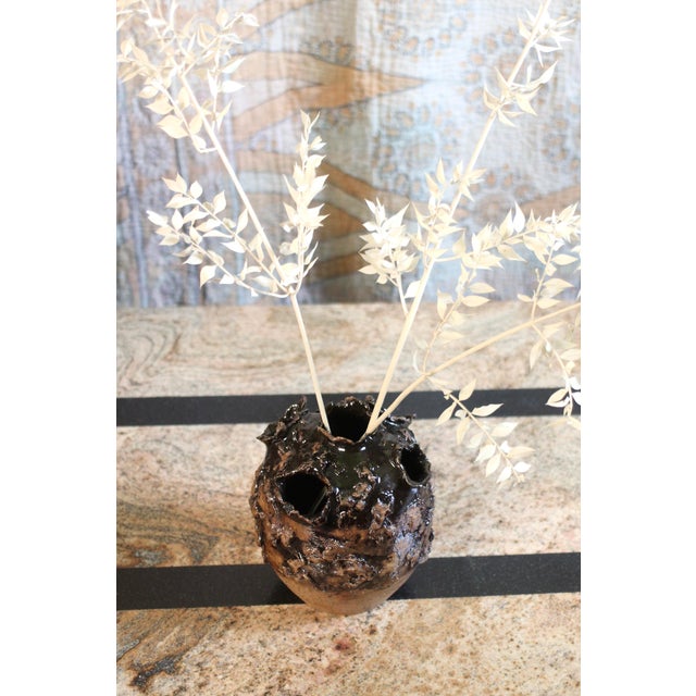 Wonderful larger tulip vase in browns with an organic texture on the holes and surface. Shiny brown glaze changing to a...