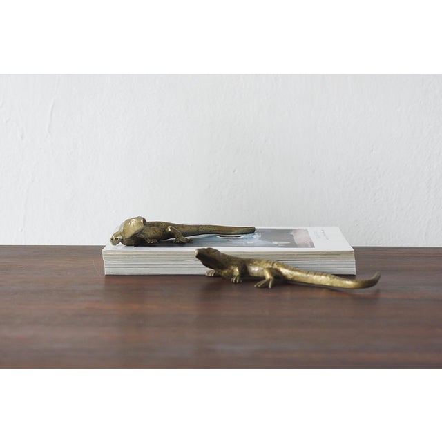 The figurine depicts a lizard in a realistic pose with its tail outstretched and limbs spread, as if it were in motion....