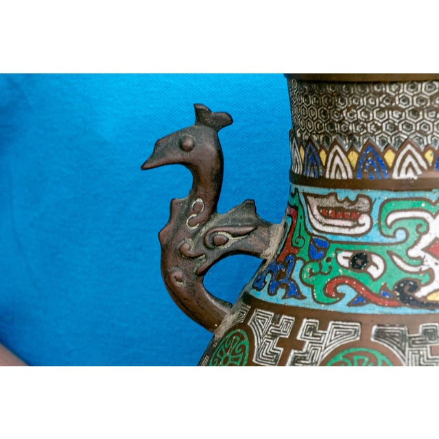 An antique Japanese cloisonné enamel vase with peacock-head handles and decorated with vividly colored geometric patterned...