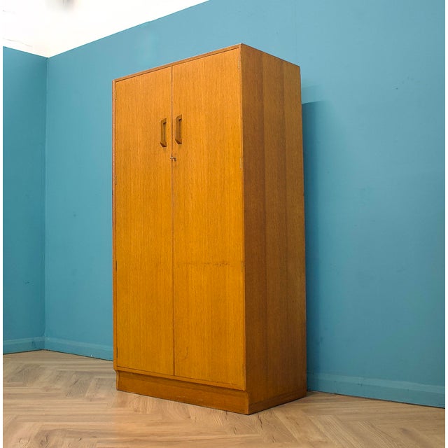 Golden oak wardrobe from the G Plan Brandon range, raised on a plinth base with original shaped wooden handles and central...