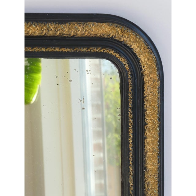 A full length French Louis Philippe style mirror with an ornate black and gold frame. The mirror dates back to the end of...