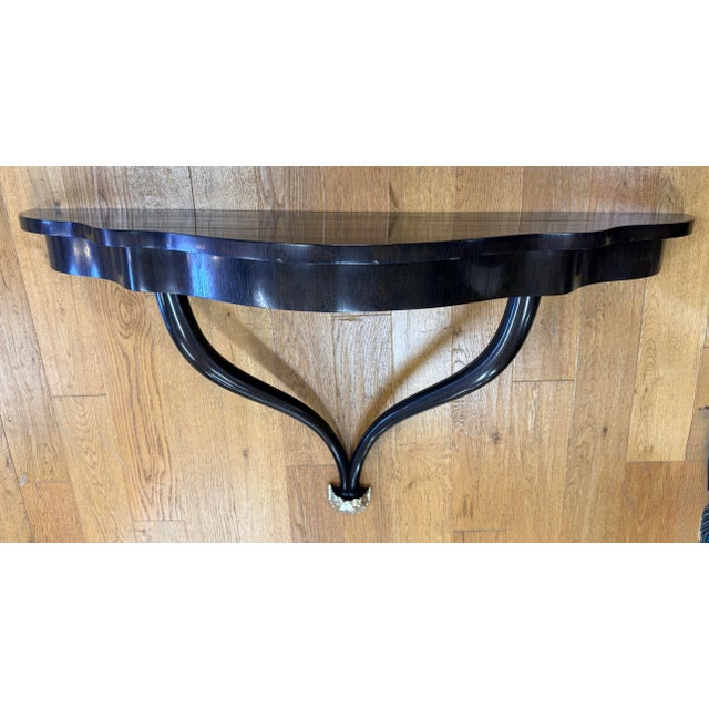Striking Art Deco–inspired wall-mounted console featuring a sculptural black lacquered wood frame with an elegantly...