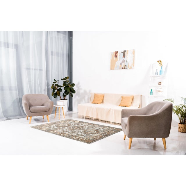 A hand-knotted wool rug, made in India and measuring 8' x 10'. Floral drawing carried across the field inside a...