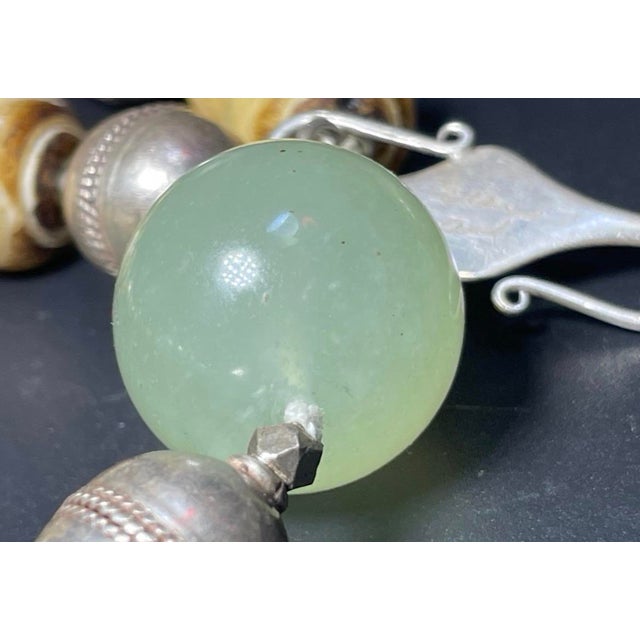 The item has large pools 23mm round beads of white celadon green jade, fossilized carved bone and sterling silver beads....