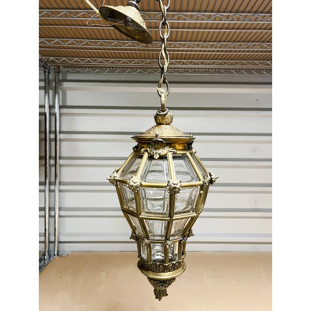 This Louis XIV style lantern pendant was made in the Early 20th Century. It consists of a beautifully crafted brass frame...