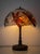 A dragonfly lamp after the model Tiffany Studios introduced around 1900 with a domed leaded-glass shade on a cast bronze...