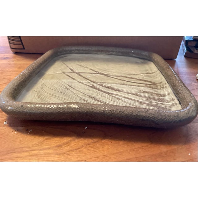 Hand thrown and fired ceramic plate has a smooth, glossy surface with delicate, etched lines that evoke the graceful...