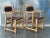 A handsome pair of vintage mid-century Ranch Oak arm chairs featuring solid oak frames with woven leather strap backs and...