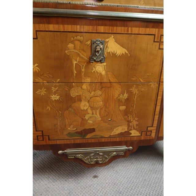 A 20th-century marquetry commode in the Transitional style. This commode, with canted corners and a projecting front,...