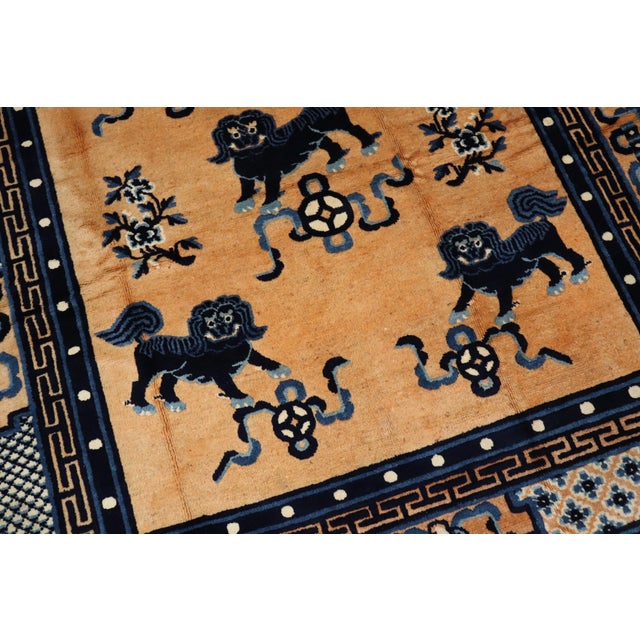 Compelling Chinese rug with a motif full of happy foo dogs, circa 1940. The field is a peach tone, with navy and light...
