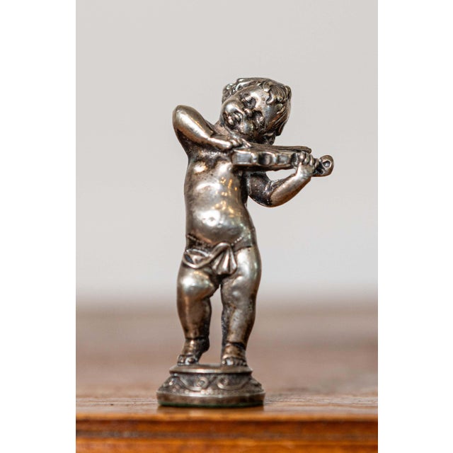 This charming early 20th-century French miniature statuette captures the playful elegance of a cherubic figure joyfully...