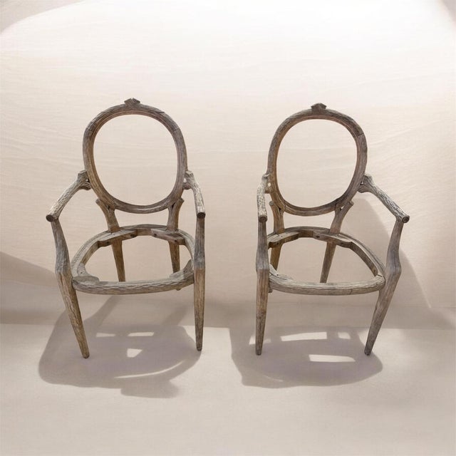 Striking pair of vintage carved wood armchairs featuring an unusual combination of refined Louis XVI-inspired form and...