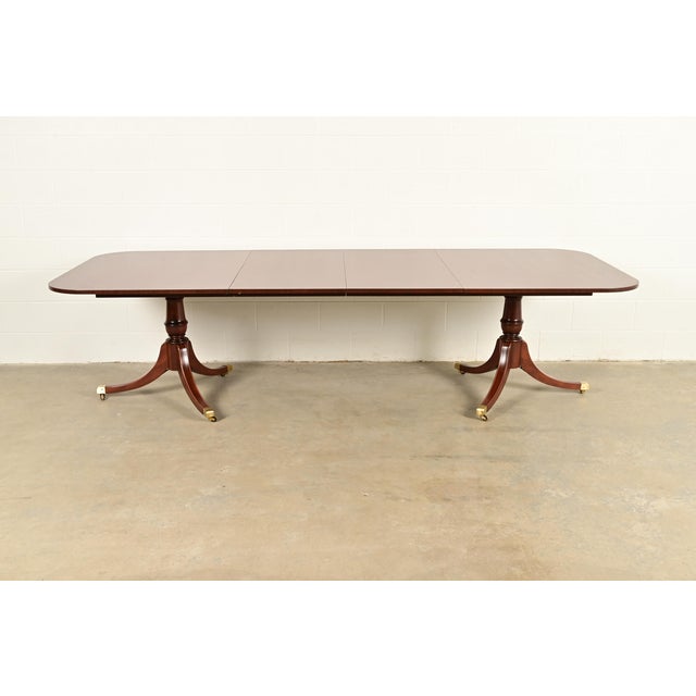 An exceptional Georgian or Regency style double pedestal extension dining table In the manner of Baker Furniture USA,...