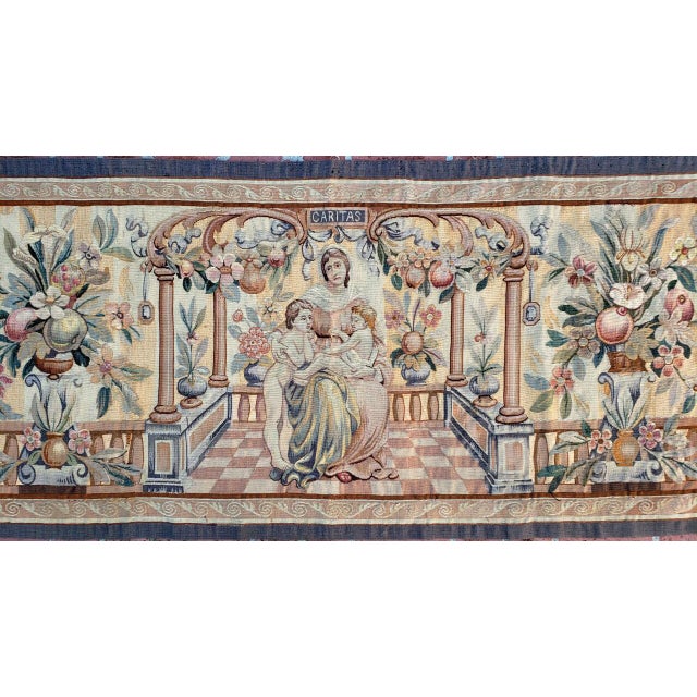 This is an antique wool and silk tapestry which is 70 x 32 inches. A lady with 2 kids are depicted on a balcony. The word...