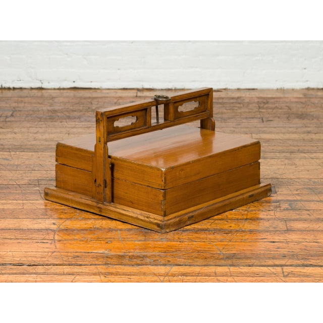 An antique Chinese wooden lunch box from the early 20th century, with large pierced handle and plinth. Born in China...