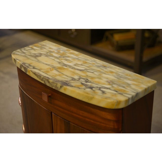 A small Art Deco entryway cabinet with a compact and elegant design, ideal as a console table. The curved body features a...