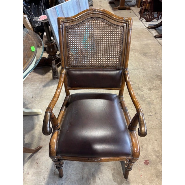 This vintage Drexel Heritage arm chair features a cane and leather backrest which is slightly arched. In the Regency...
