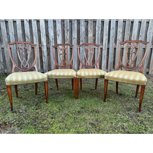 Selling this exquisite set of 4 Hepplewhite-style mahogany carved shield-back chairs with the following features: -...