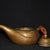 A refined, minimalist brass teapot in a softly rounded, organic form. The body swells gently from a flat base and is...