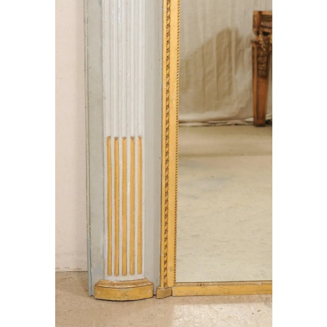 A large French over-mantle mirror with architectural accents from the 19th century. This antique mirror from France has a...