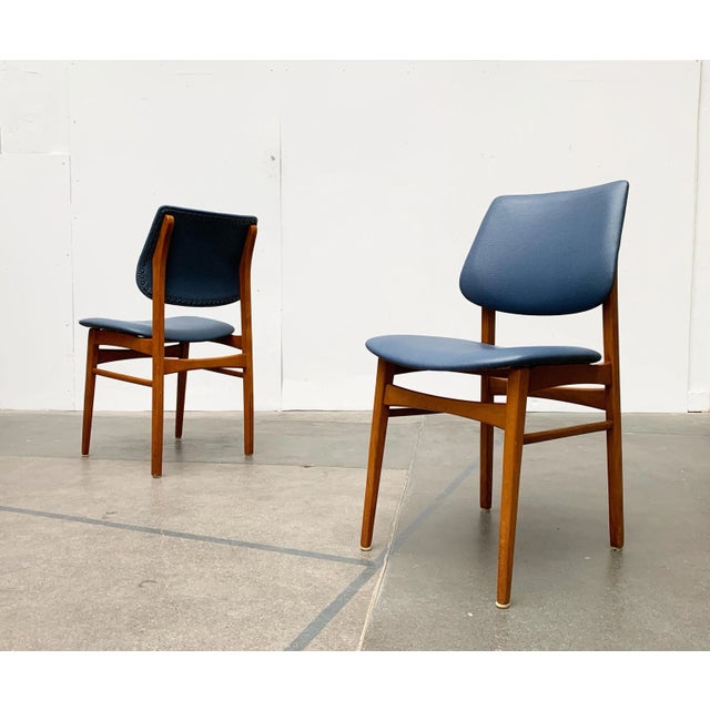 Elegant Mid Century chairs with blue imitation leather upholstery. The frame of the chairs is composed of solid wood...