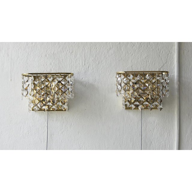 A pair of brass and crystal glass wall lamps by Palwa. It is a proposal of decorative lighting for sophisticated interiors...