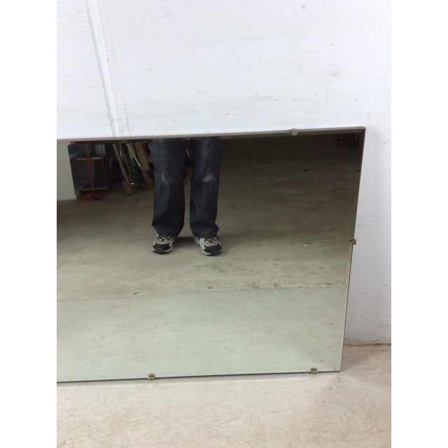 This mid century modern mirror features large vintage mirror glass with beveled edge and brass accents on a hard wood frame.