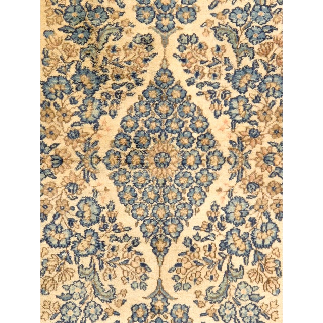 An antique Persian Lavar rug featuring an elegant floral medallion design on an beige field, framed by a deep navy floral...