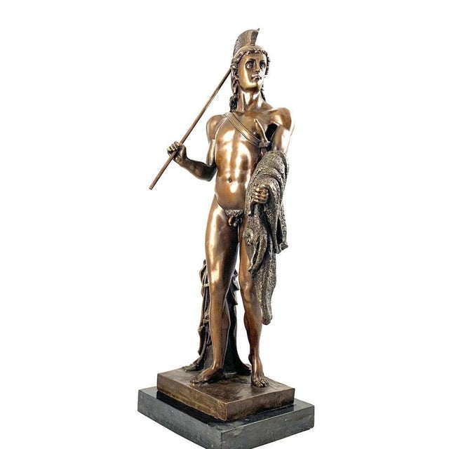A cast bronze figure of a classical greek warrior. Dark brown patination. Shown standing holding a spear a cloak draped...