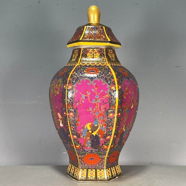 A striking Chinese porcelain vase featuring a vibrant pink ground. The vase has a faceted, hexagonal baluster shape with a...