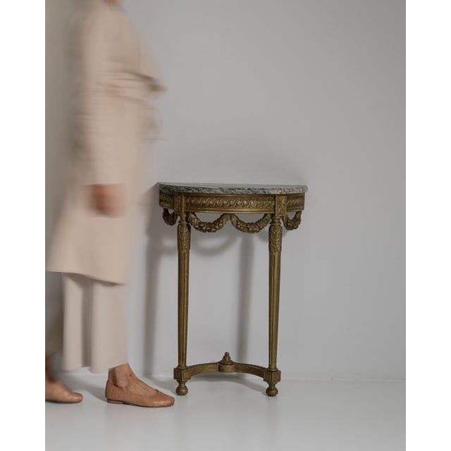 This early 20th century Louis XVI giltwood console table with marble top from France is carved in giltwood with slender...