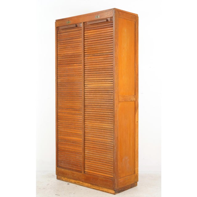 Vintage European office storage cabinet with Mid Century styling. The tambour doors latch and lock at the top, sliding...