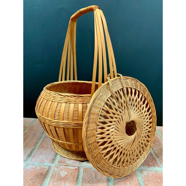 Woven rattan and bamboo lidded basket imported from China in the mid to late 20th century. The lid is intricately woven...