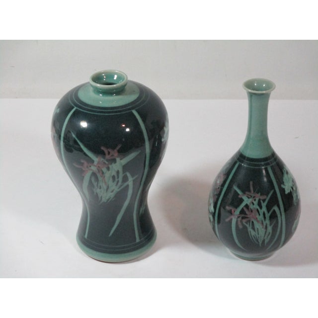 Set of two celadon crackle Korean porcelain vases. They have four decorative panels, hand-painted with various raised...