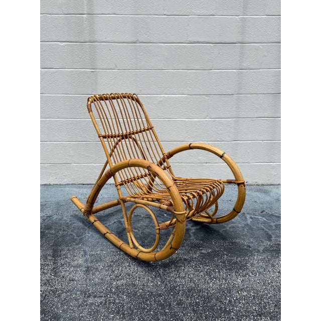 A sculptural vintage rattan rocking chair in the style of Franco Albini, defined by its fluid bentwood lines and signature...