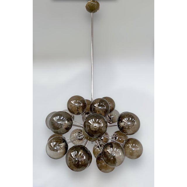 Italian oval shaped sputnik chandelier with 24 smoky Murano glass globes carefully hand blown with bubbles inside the...