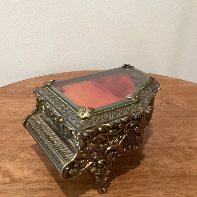 Beautiful piano musical jewelry box featuring cast metal body, elaborate floral and acanthus leaf scrolling swags on all...