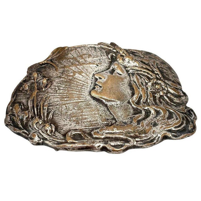This exquisite Alphonse Mucha-inspired buckle features a captivating Art Nouveau design, showcasing a finely detailed...