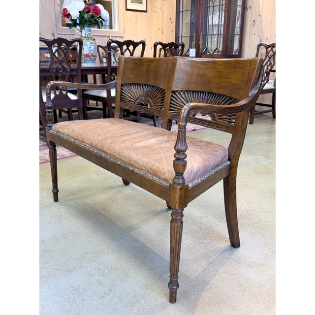 A distinguished 1940s mahogany settee showcasing refined craftsmanship and subtle decorative flair. The open backrest...