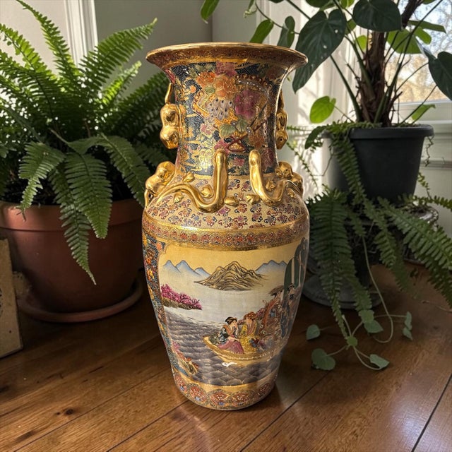 This vase features traditional scenes of figures in boats against a mountain landscape. It includes raised enamel...
