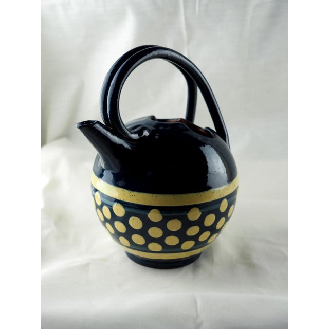 Glazed earthenware jug, spherical shape with trefoil opening, double handle, decorated with a frieze of bright yellow...