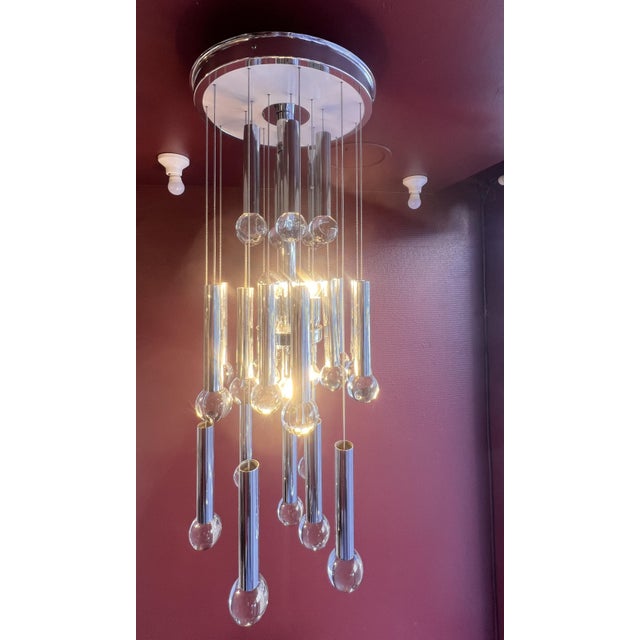 Glass and chrome chandelier by Gaetano Scolari, Milan, 1960s. Central stem composed of four bulbs whose light is reflected...