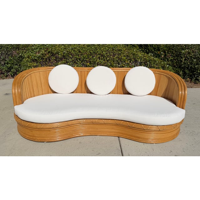 Gorgeous vintage curved sofa! This is a rare gem featuring a sculptural design constructed of pencil reed rattan over a...